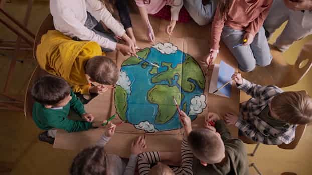 aerial view of children working together on a painting of earth